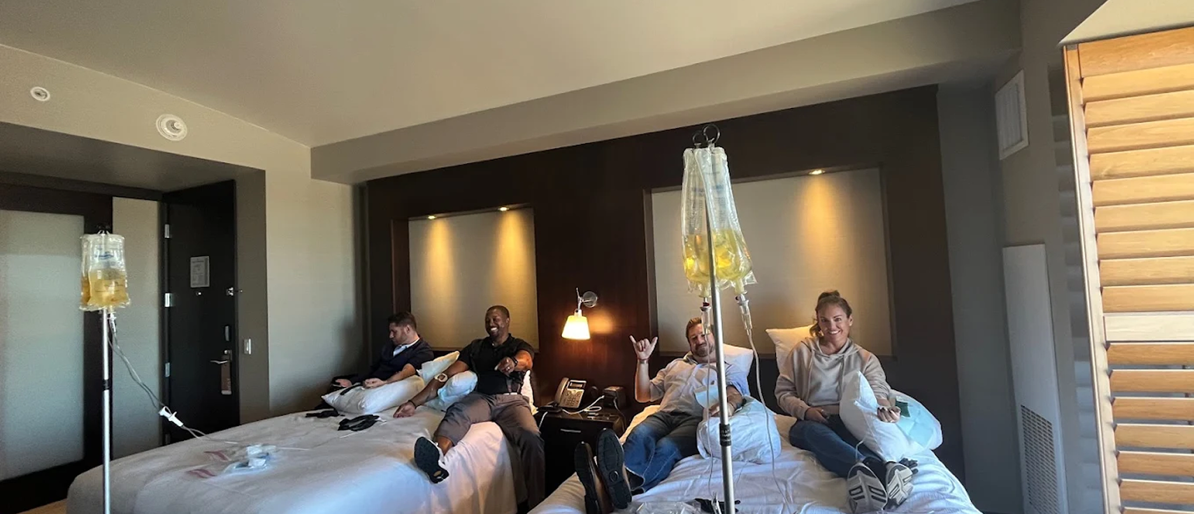 Group of people receiving IV drip therapy in hotel room
