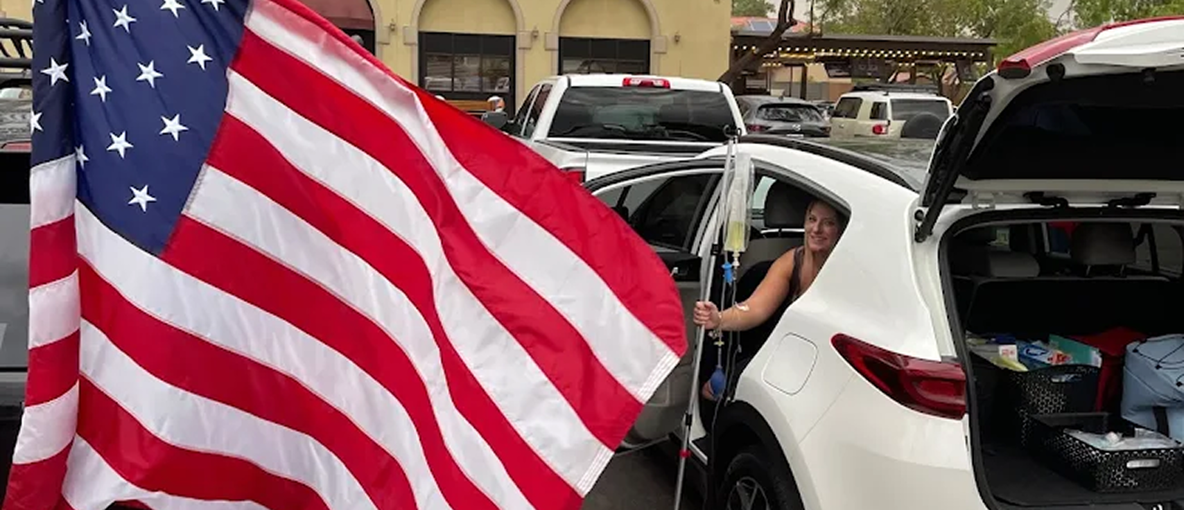 Woman receiving mobile IV therapy while sitting in car with American flag