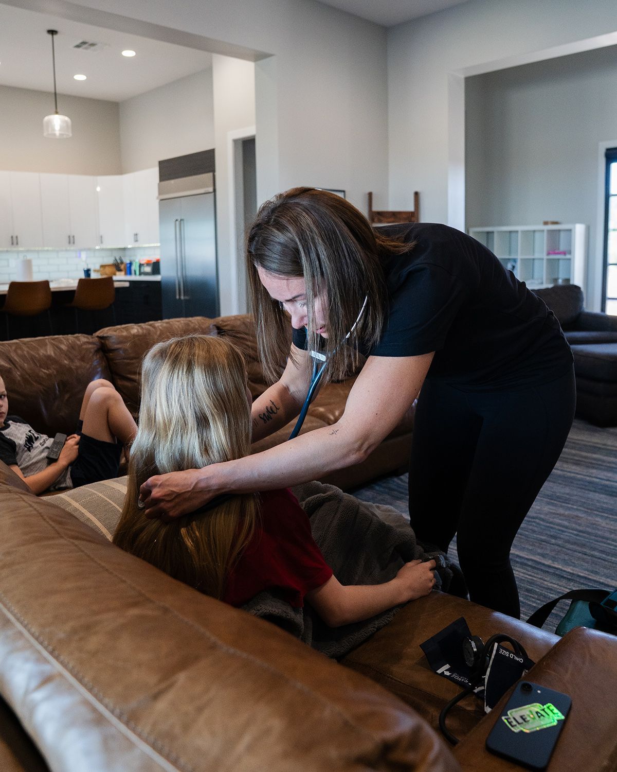 Nurse examining patient with stethoscope during home medical visit