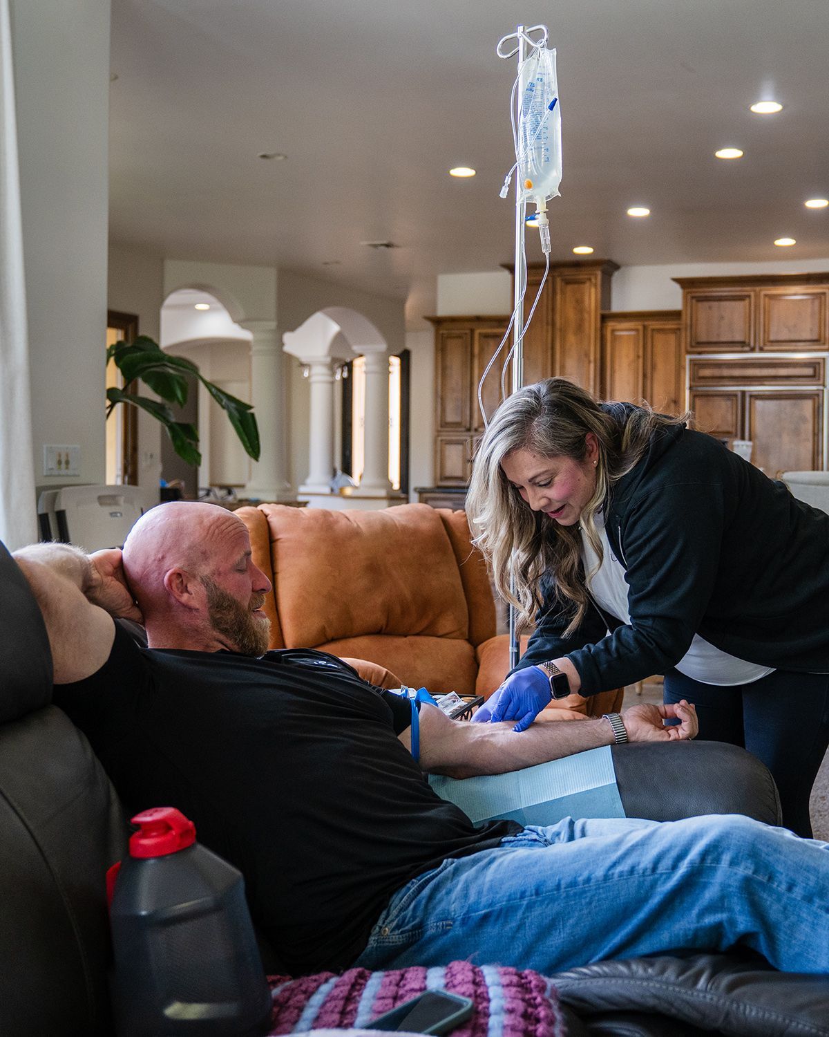 Nurse administering IV drip to man at home