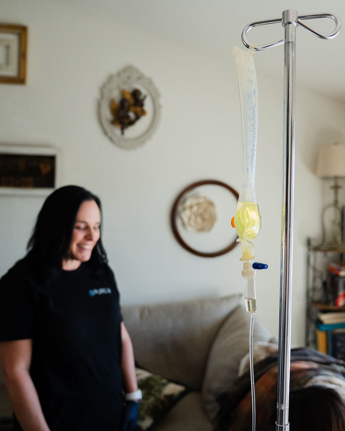 IV therapy bag hanging on pole with nurse smiling in background
