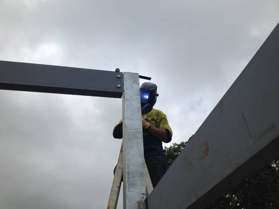 Welder in protective gear welding metal beams outdoors under a cloudy sky - North Coast Steel Fabrication in South Lismore, NSW