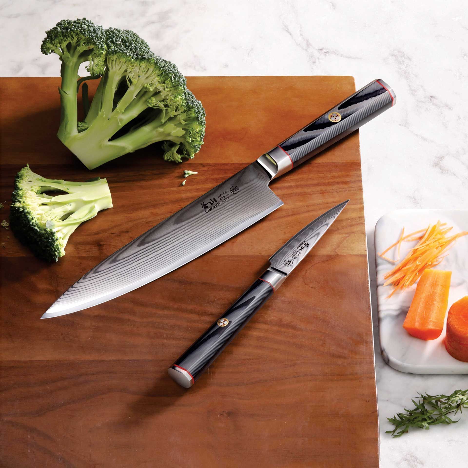 A cutting board with broccoli carrots and knives on it