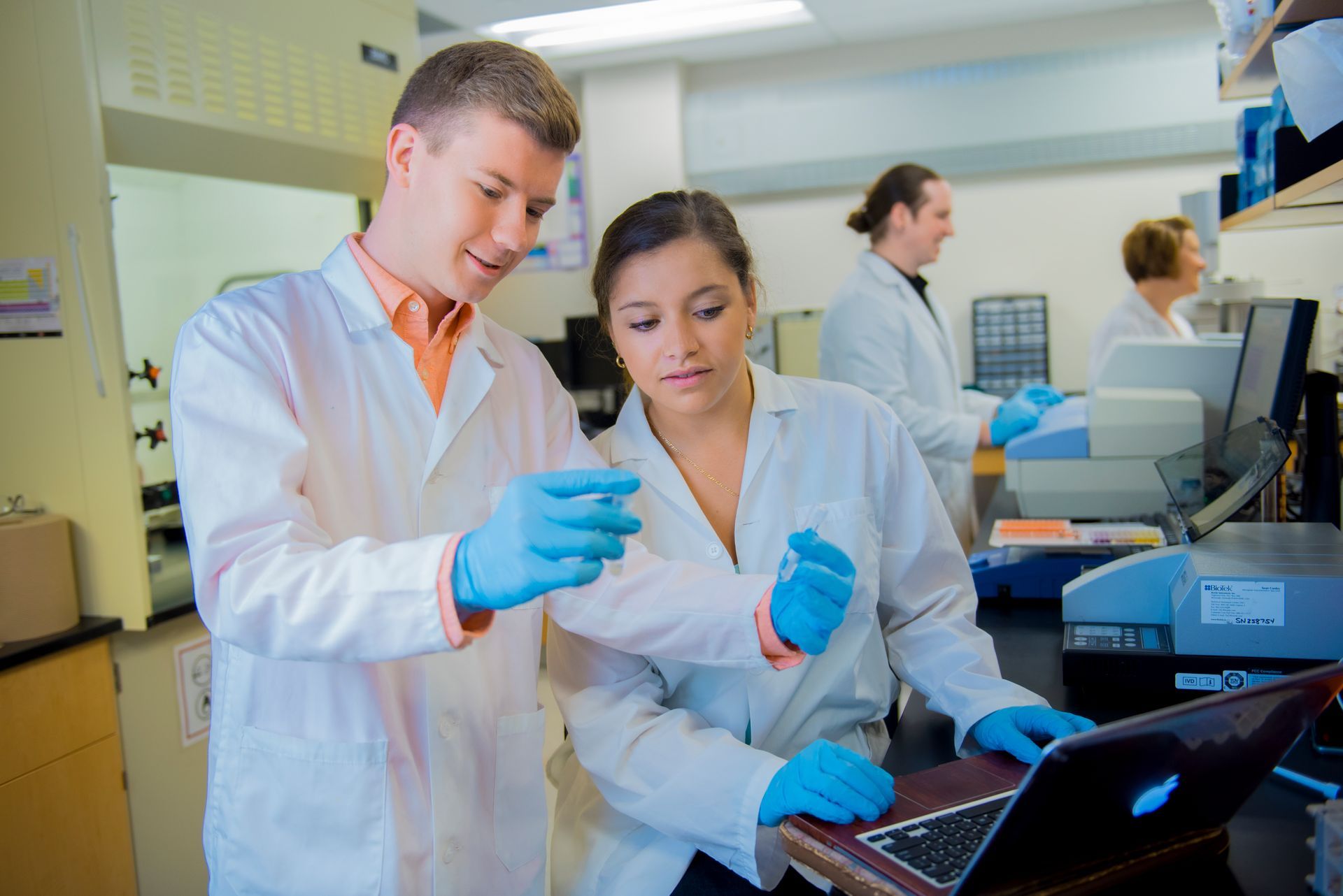 A man and a woman are looking at a laptop in a lab.
