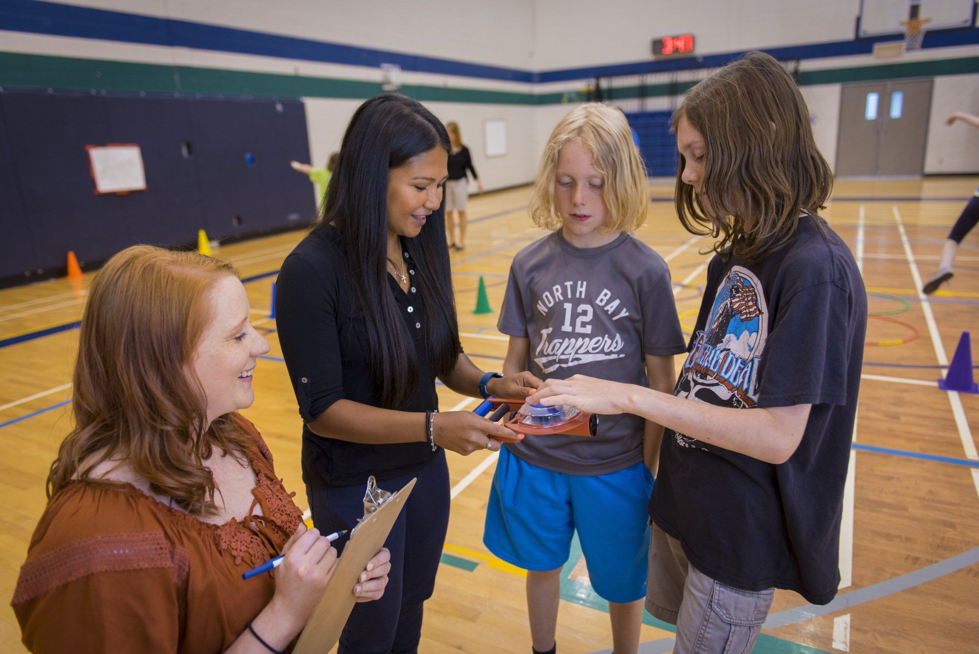 A group of people are standing in a gym talking to each other.