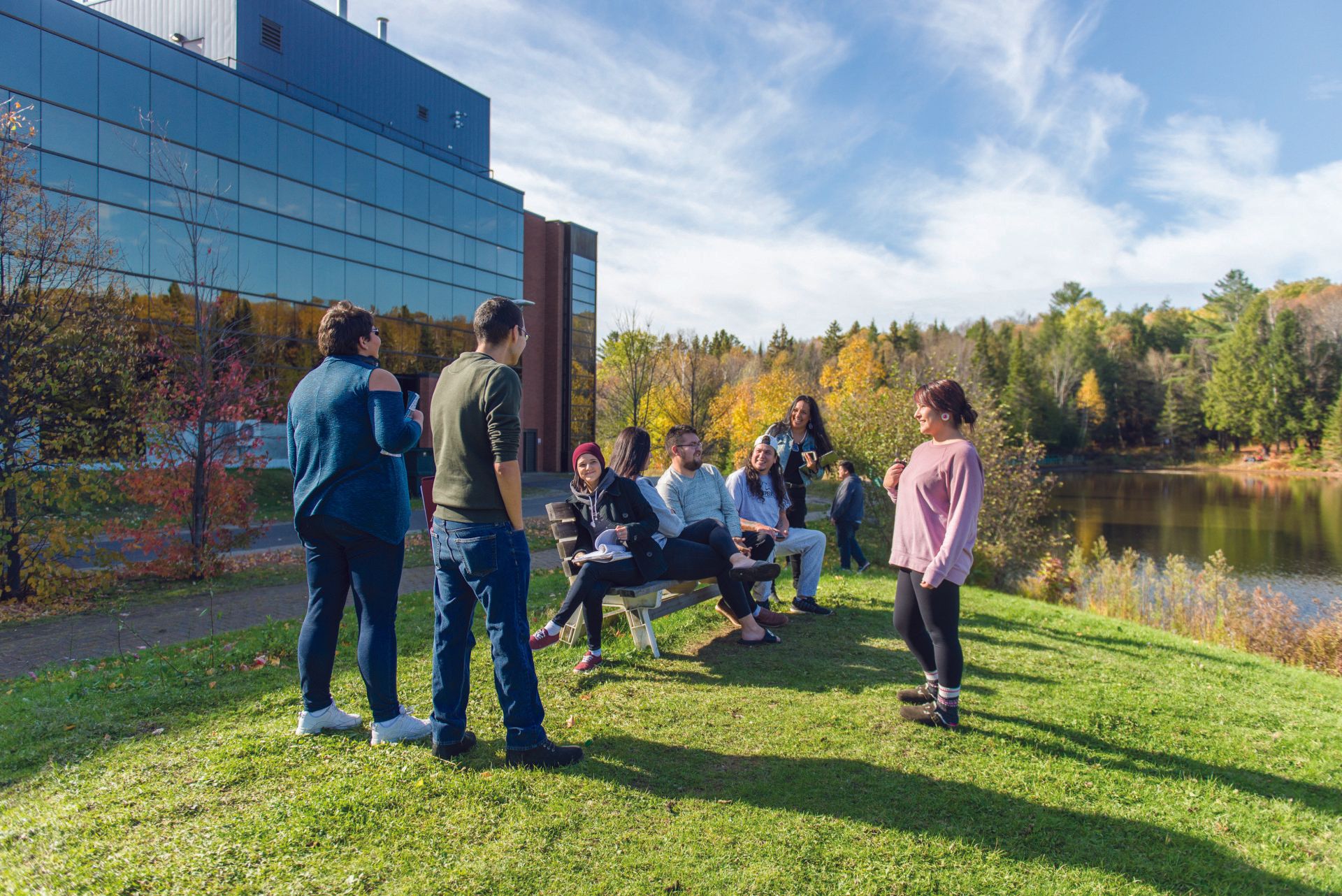 A group of people are standing in the grass in front of a building.