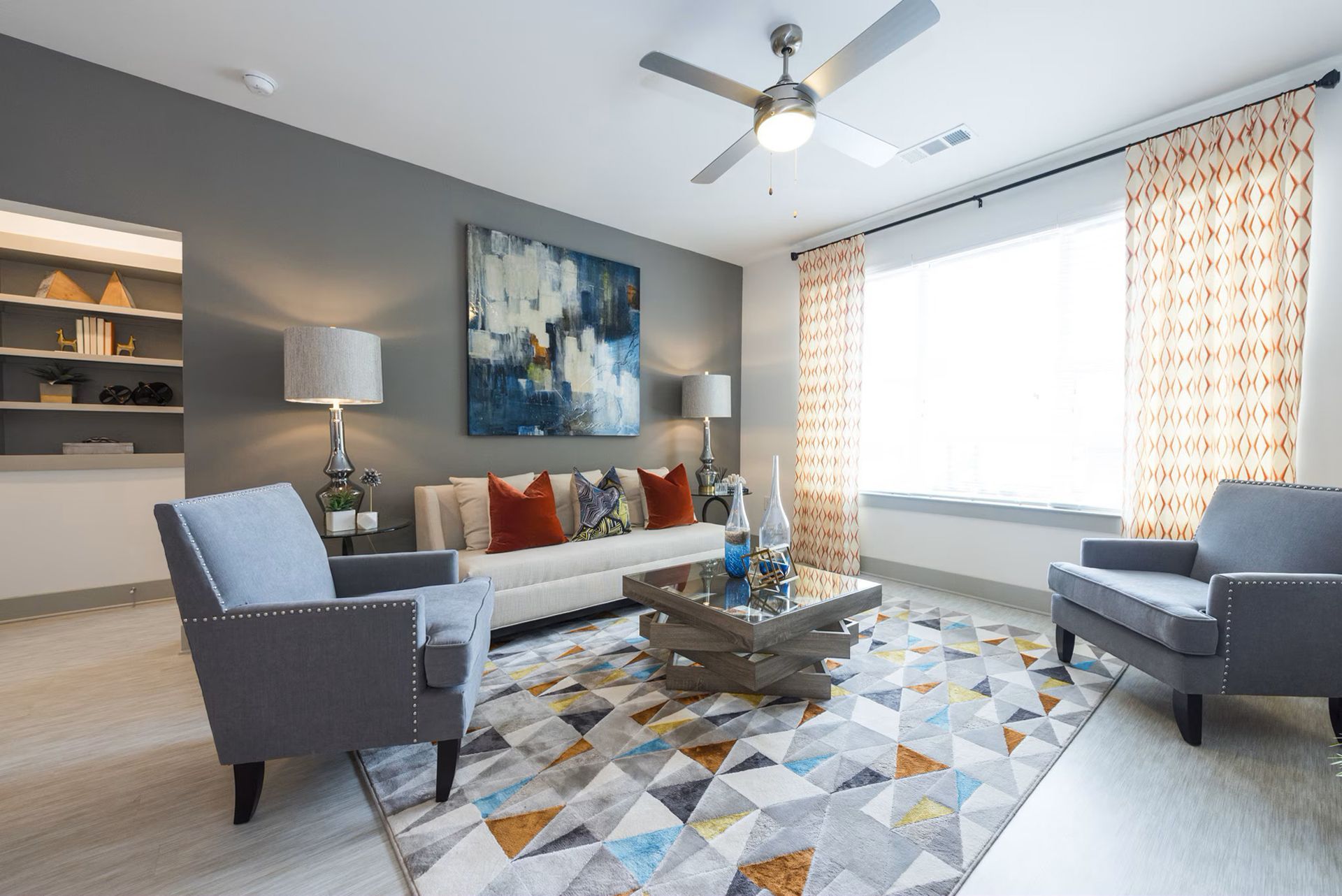 Living room with gray walls, blue and orange accents, modern furniture, and a geometric rug.
