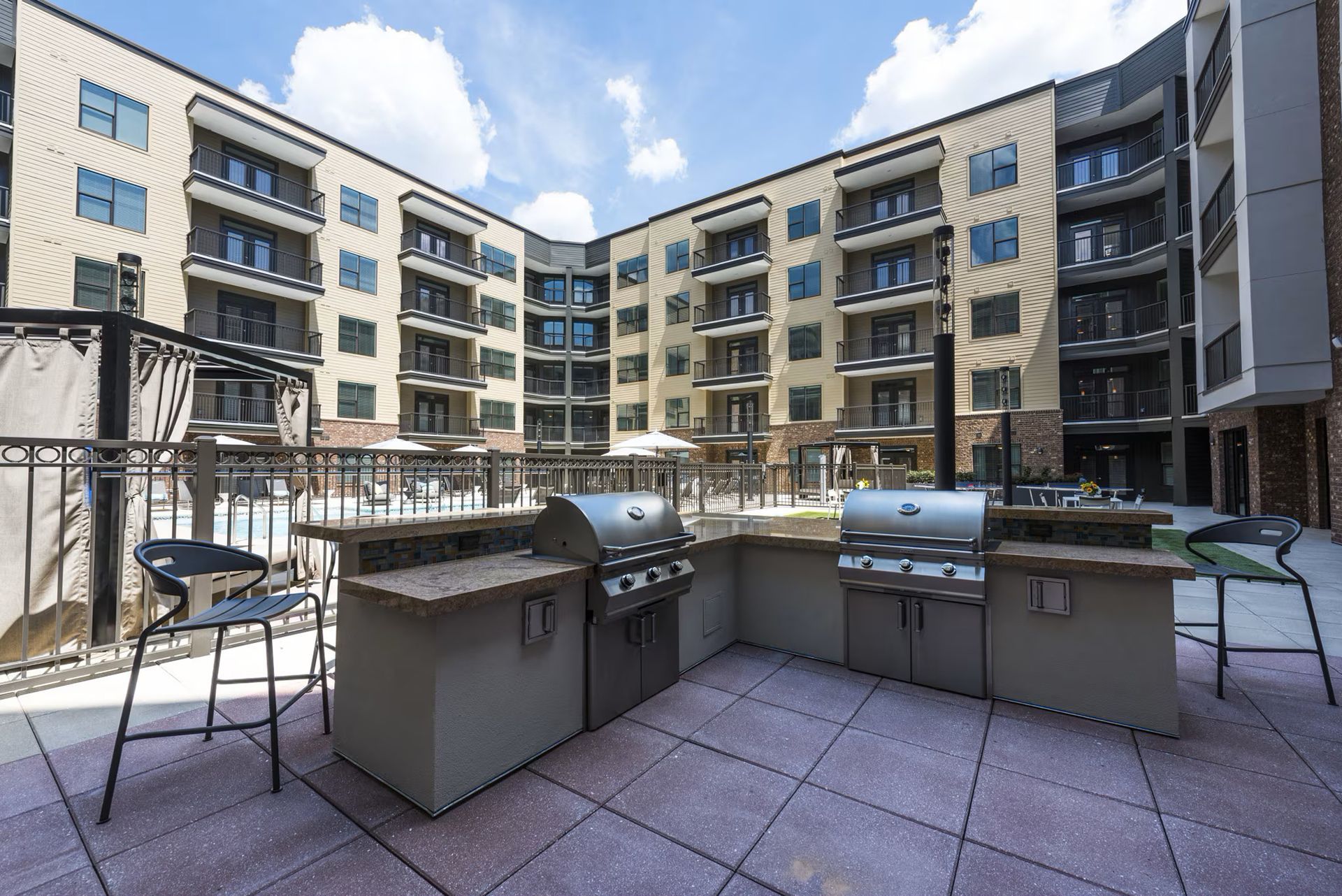 Outdoor kitchen with grills and seating in front of a modern apartment complex.