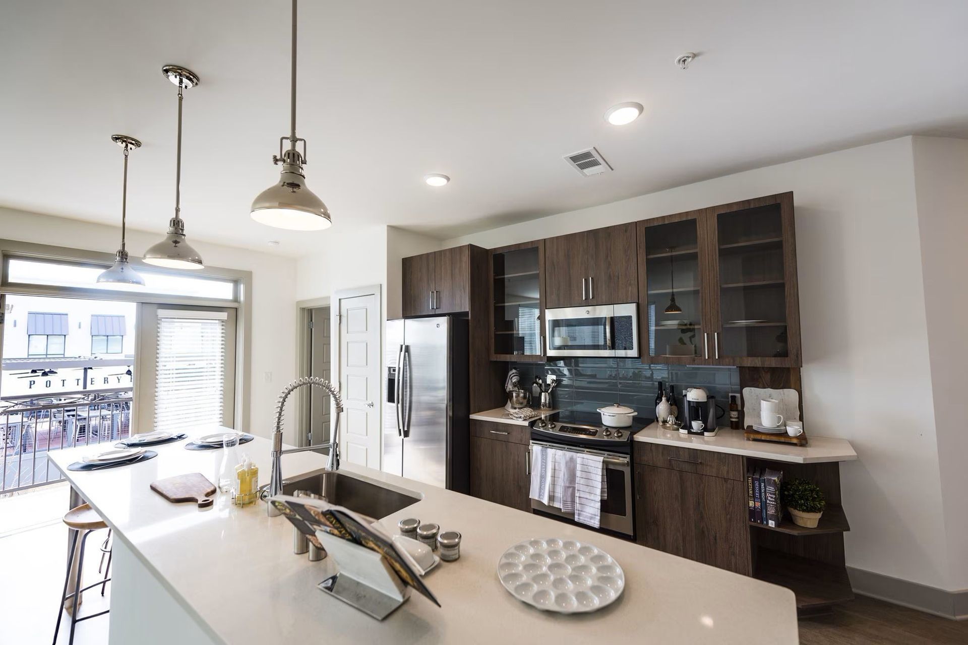 Modern kitchen with dark wood cabinets, stainless steel appliances, and a white island.