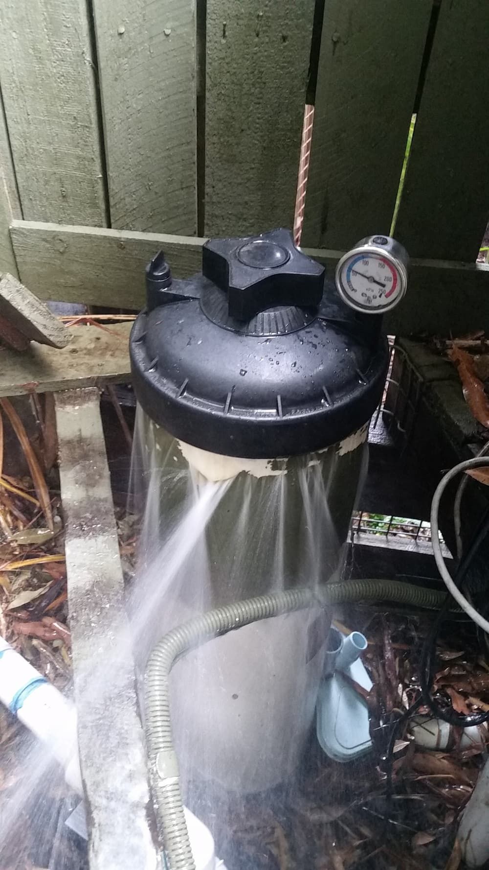 A Water Filter Is Being Cleaned with A Hose and Spray Bottle — Poolside Noosa in Noosaville, QLD