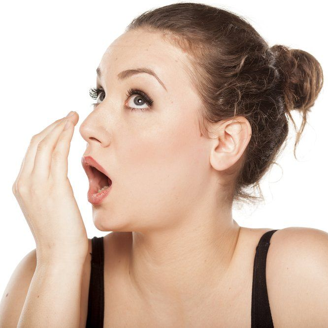 Woman covering mouth with hand, looking up with surprised expression.