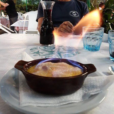 Dessert flambato in un piatto marrone su un tavolo di un ristorante all'aperto.