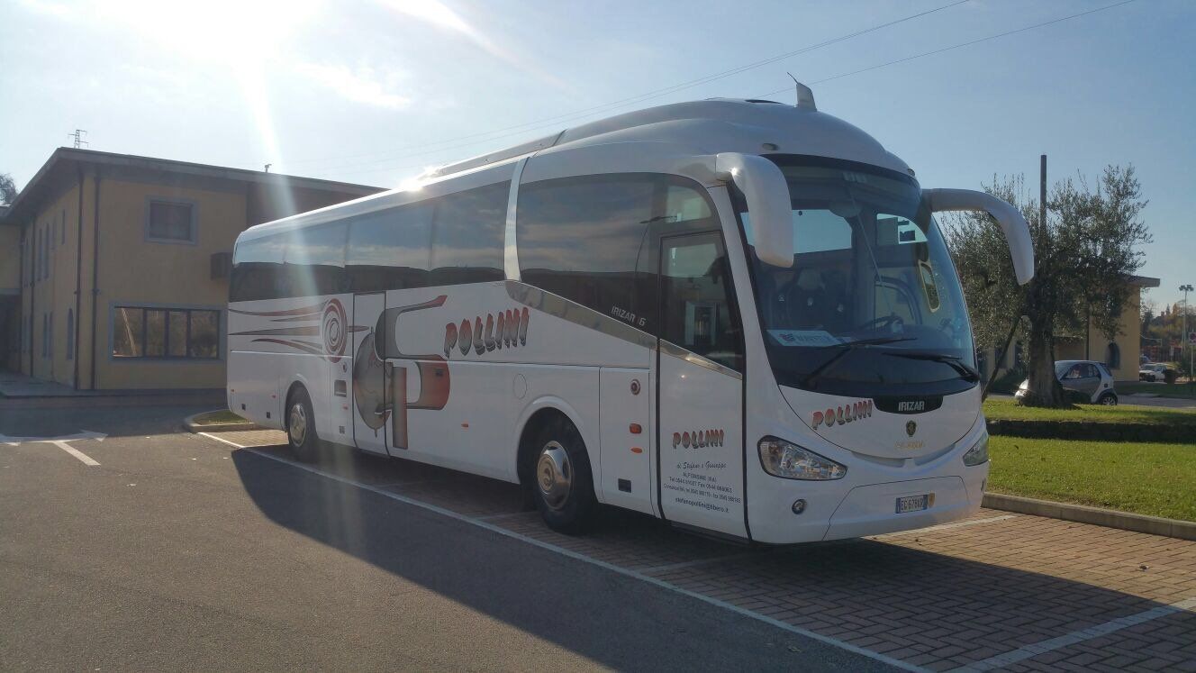White coach parked in front of a building; daytime.
