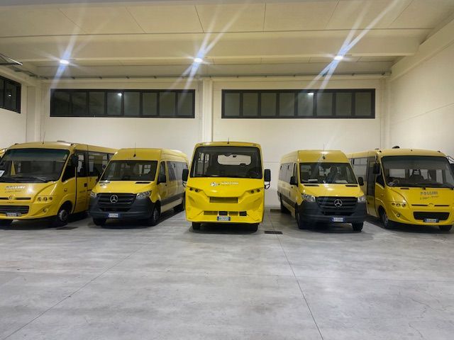 Five yellow school buses parked inside a well-lit garage.