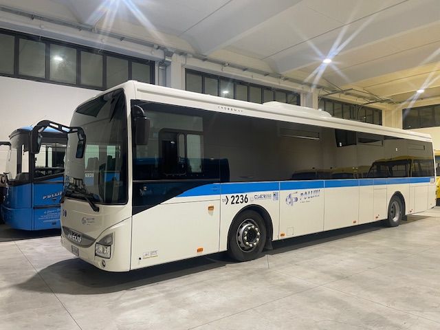 White bus with blue stripe, parked inside.