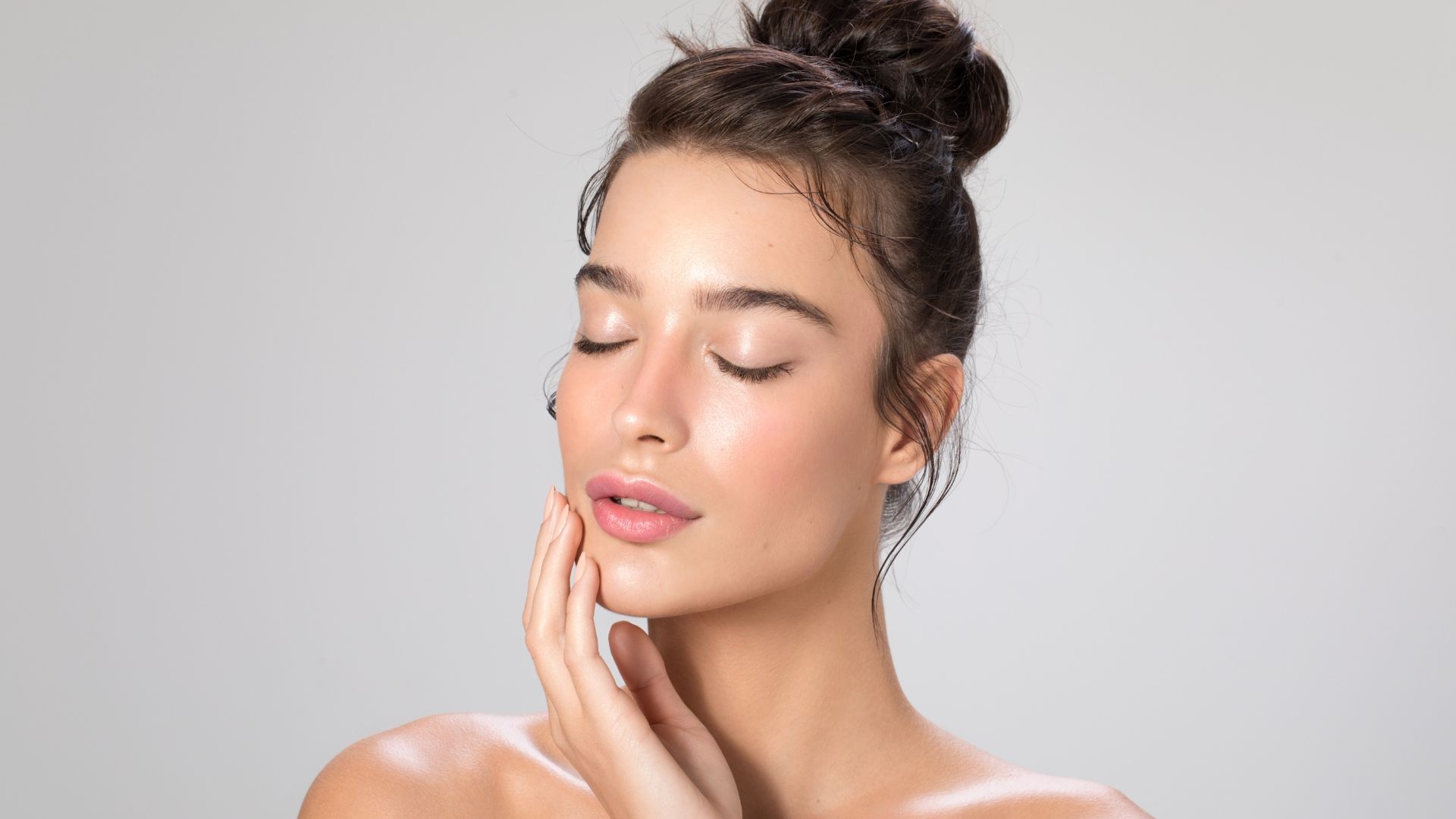 A woman with her eyes closed is touching her face with her hand.