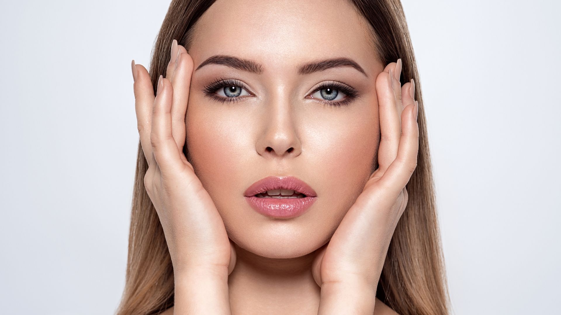 A close up of a woman 's face with her hands on it.