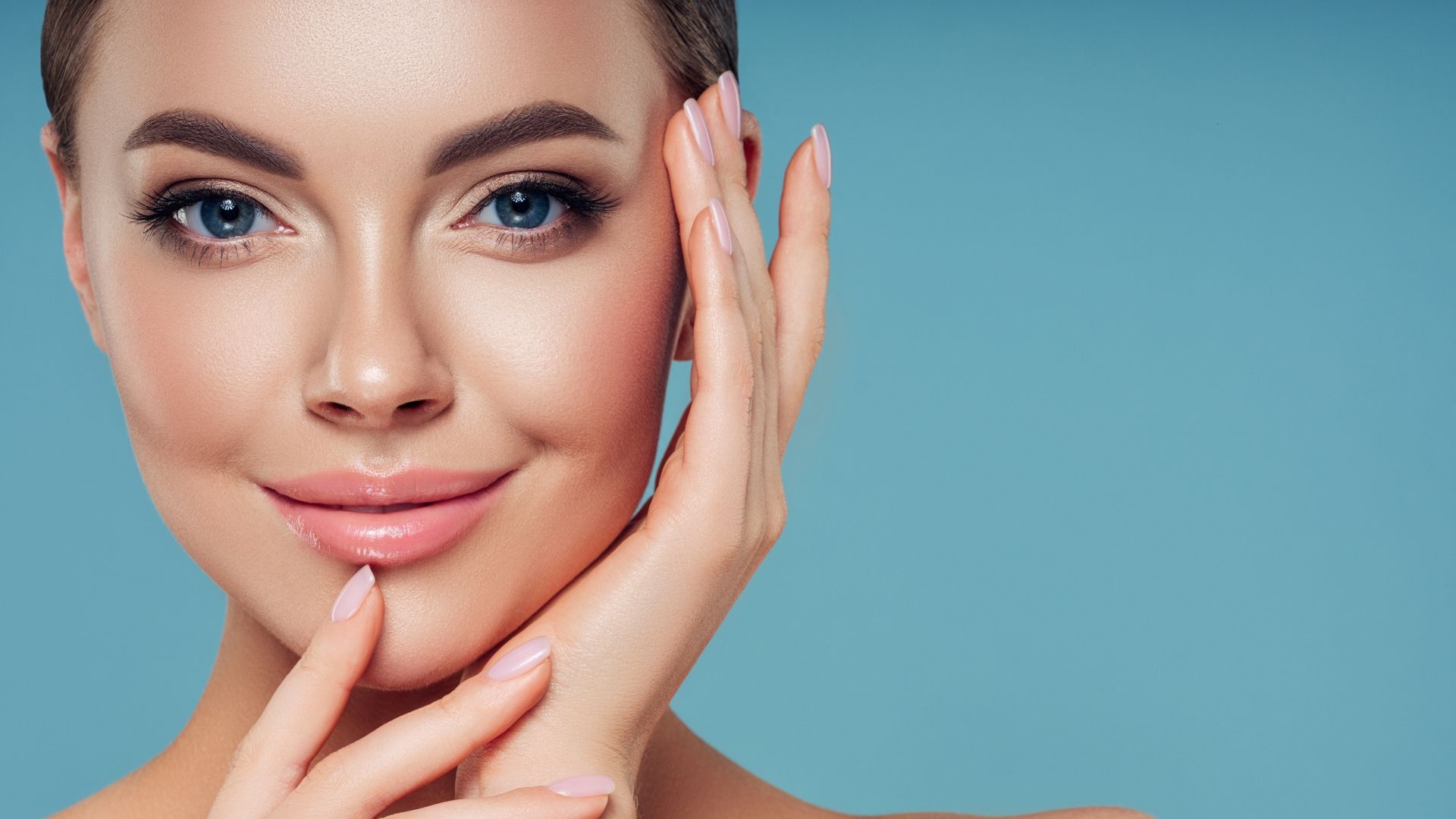 A woman is touching her face with her hands and smiling.