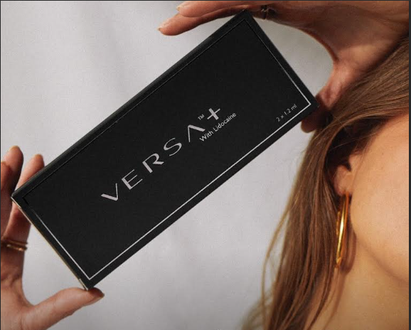 Black VERSA+ box held beside a person's ear against a white background
