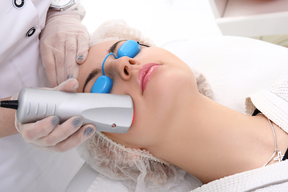 A woman is getting a laser treatment on her face.