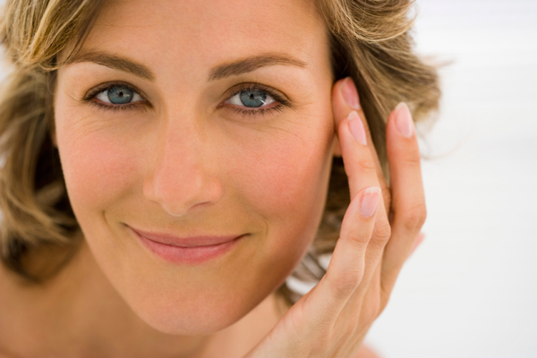 A woman is smiling and touching her face with her hand