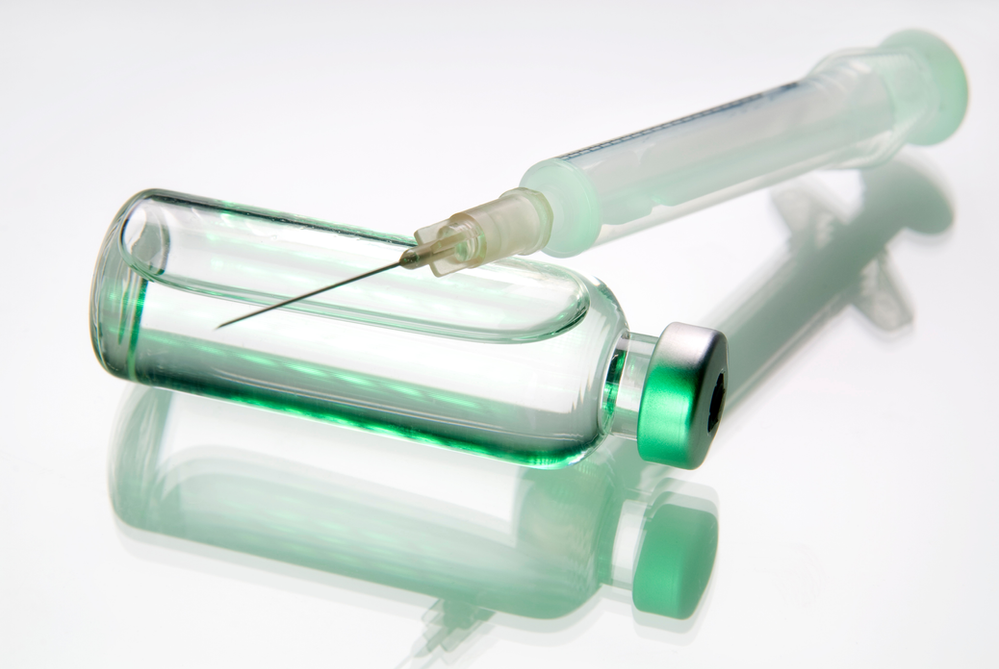 A syringe is sitting next to a bottle of liquid