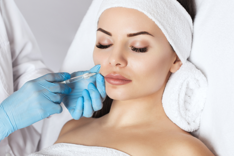 A woman is getting a botox injection in her lips.