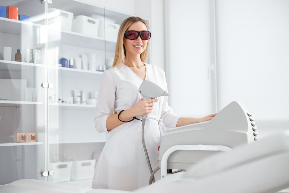 A woman is using a laser hair removal machine in a beauty salon.
