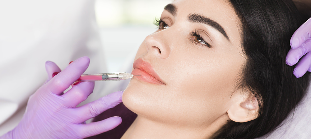 A woman is getting a botox injection in her lips.