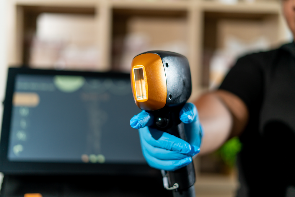 A person wearing blue gloves is holding a machine in their hand.