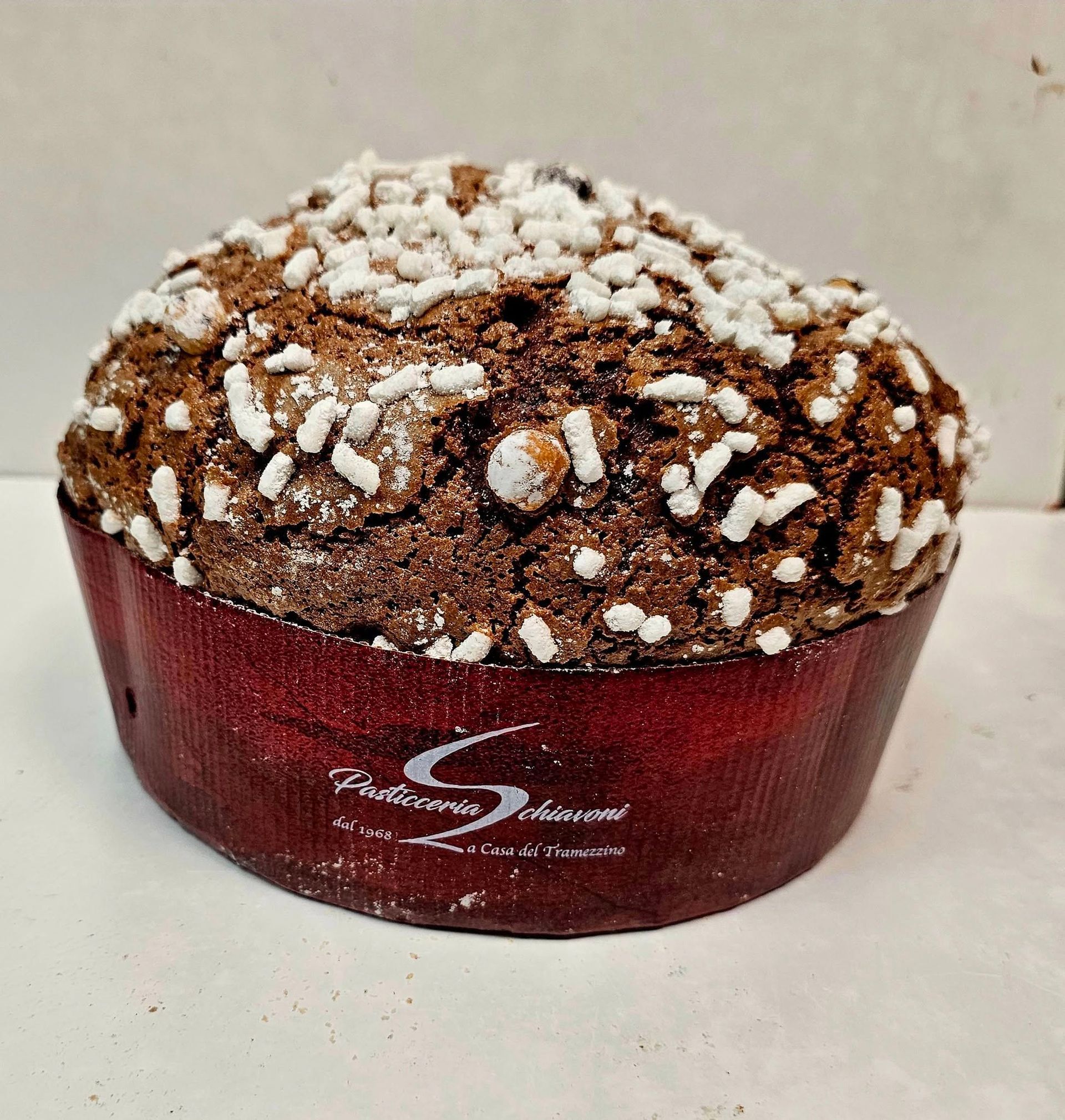 Muffin al cioccolato guarnito con cristalli di zucchero bianco in un pirottino di carta rosso.