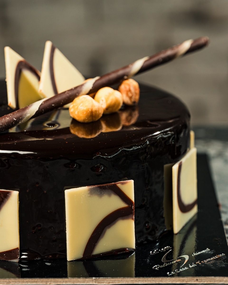 Torta al cioccolato lucida con quadratini di cioccolato bianco e nocciole in cima