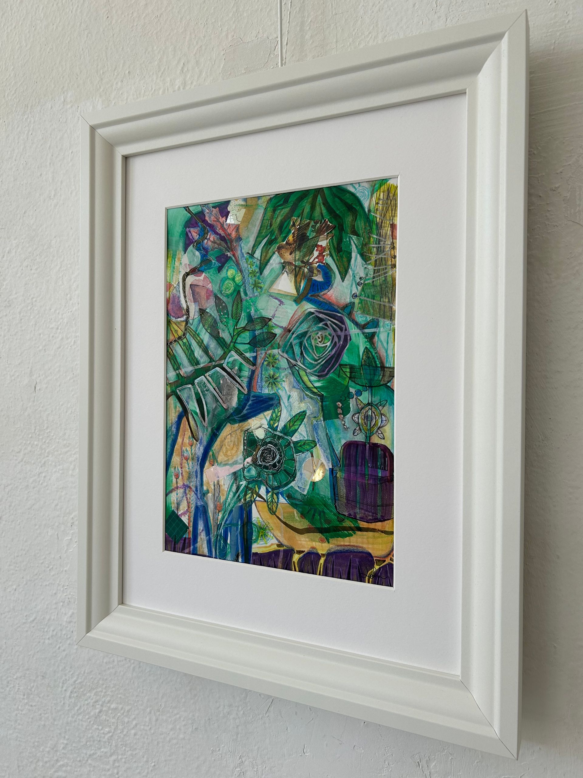 Ingelijst, kleurrijk abstract schilderij met groene, blauwe en gele patronen aan de muur.