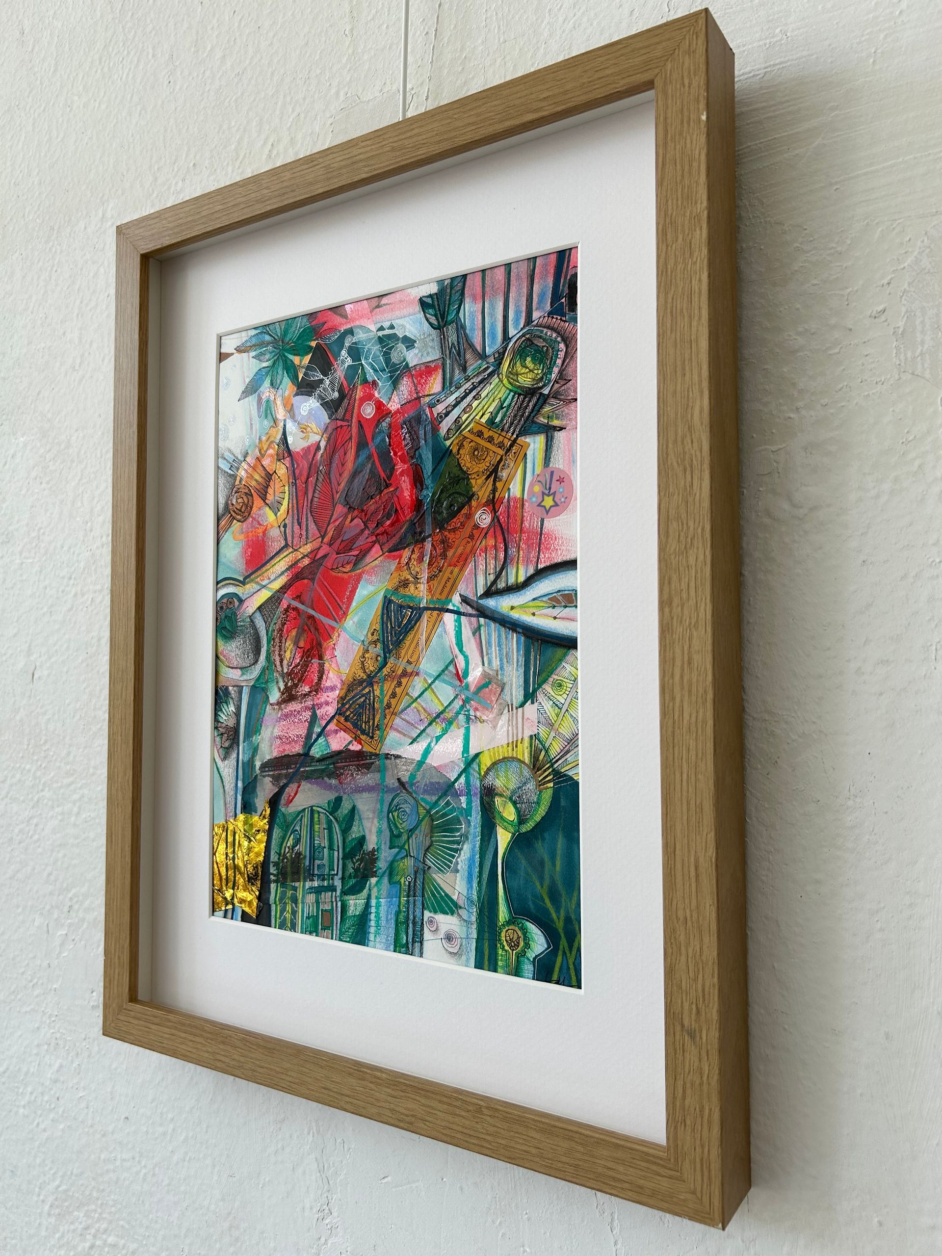 Abstract, kleurrijk schilderij in een gouden lijst op een witte muur.