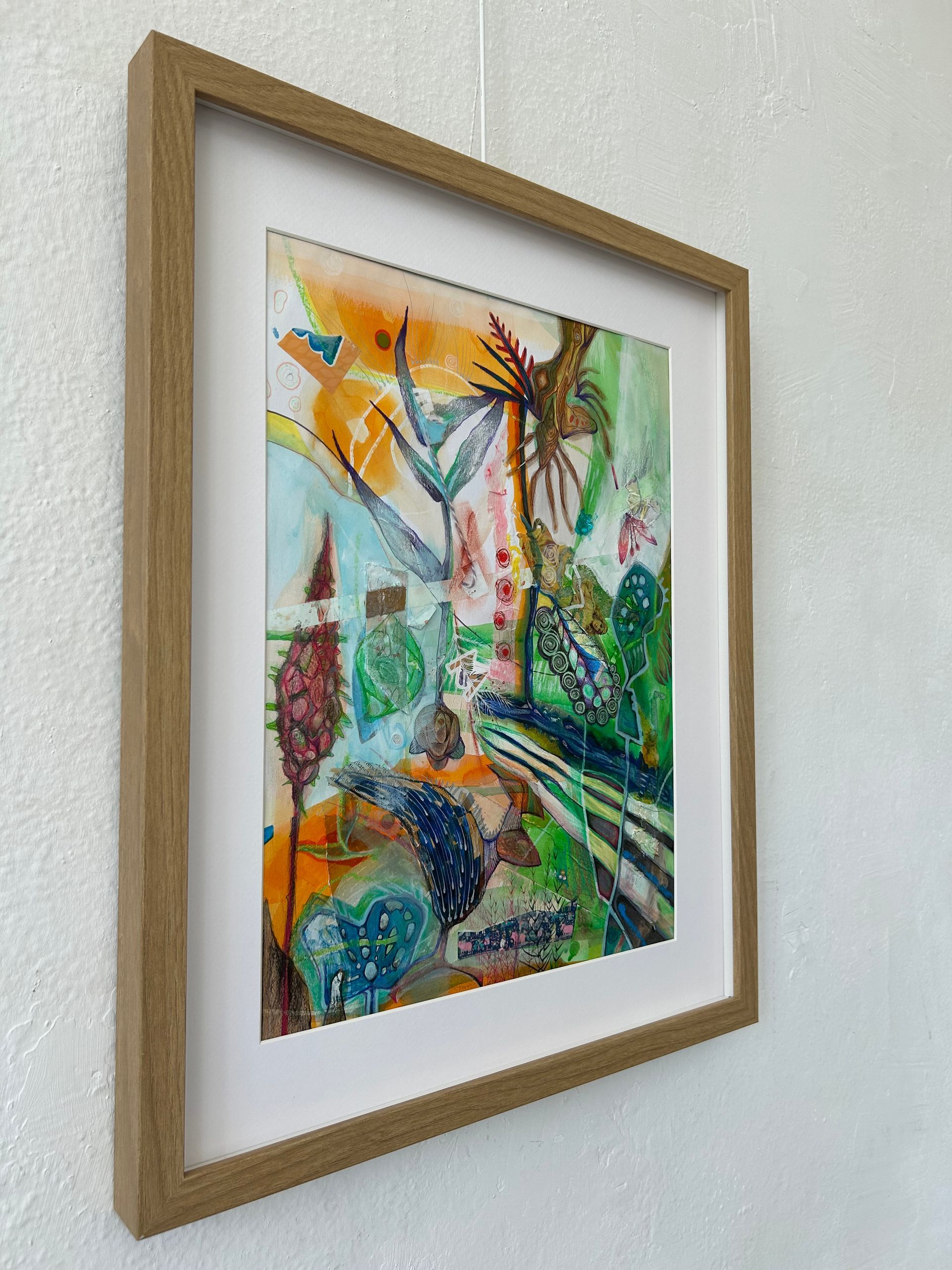 Ingelijst abstract, kleurrijk kunstwerk met oranje, groene en blauwe tinten op een witte muur.