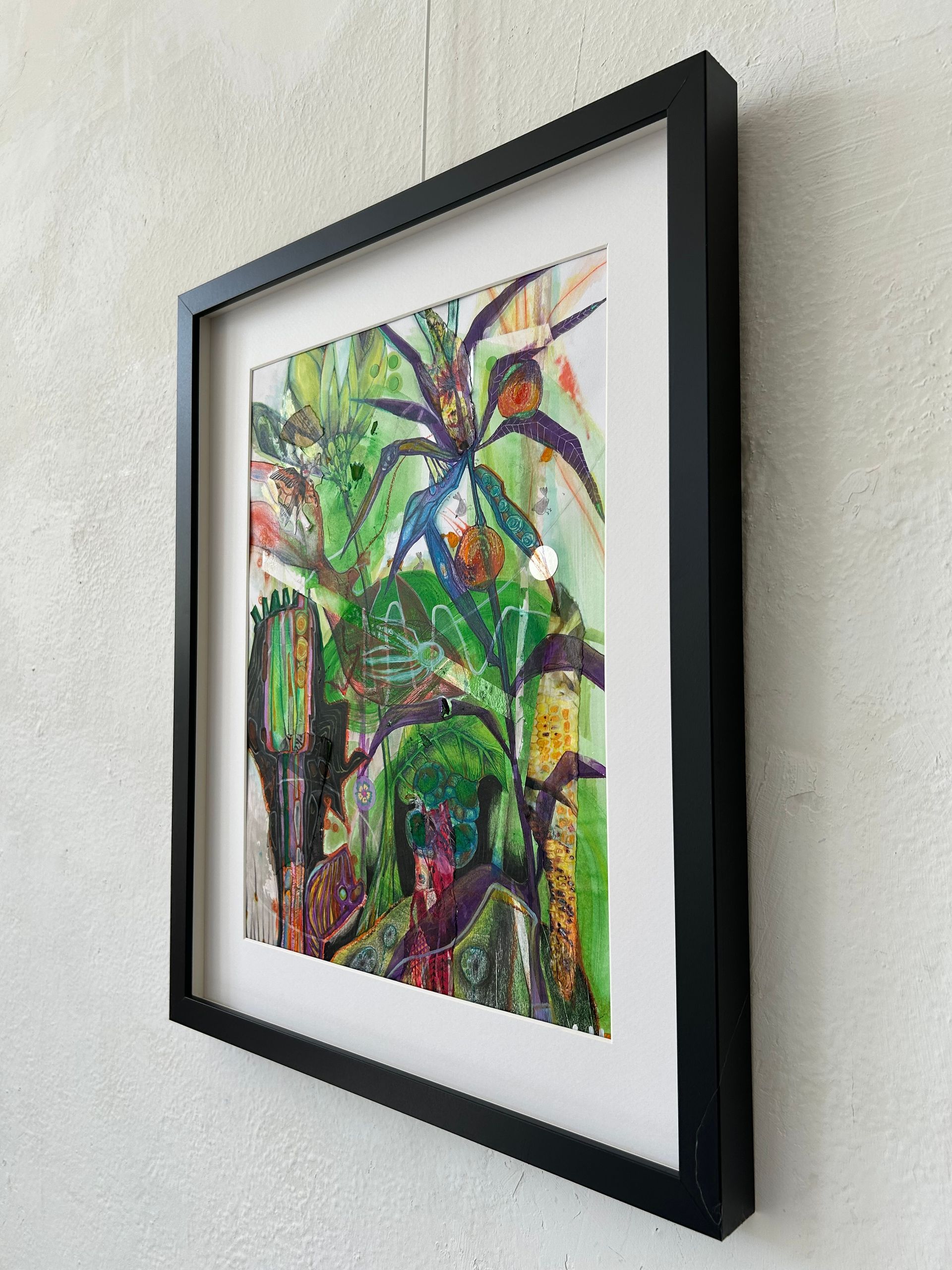 Een ingelijst, kleurrijk abstract schilderij aan de muur, vanuit een bepaalde hoek bekeken.