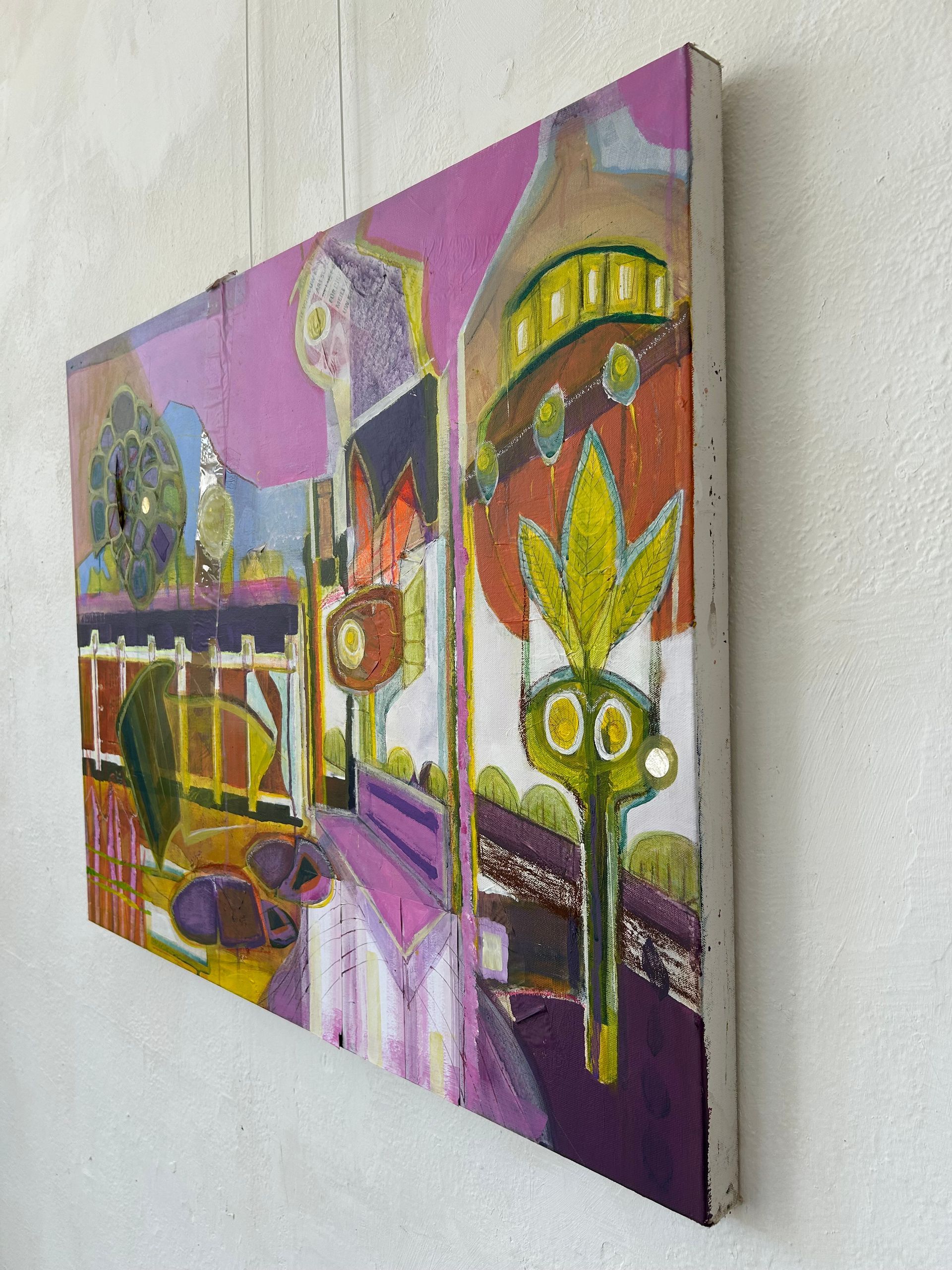 Kleurrijk abstract schilderij aan de muur, met paarse, gele en oranje stadsgezichten.
