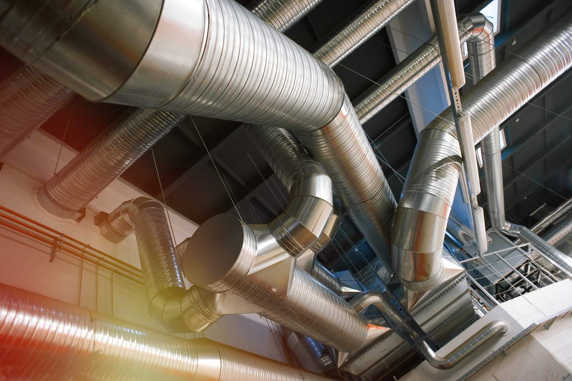 A bunch of metal pipes are hanging from the ceiling of a building