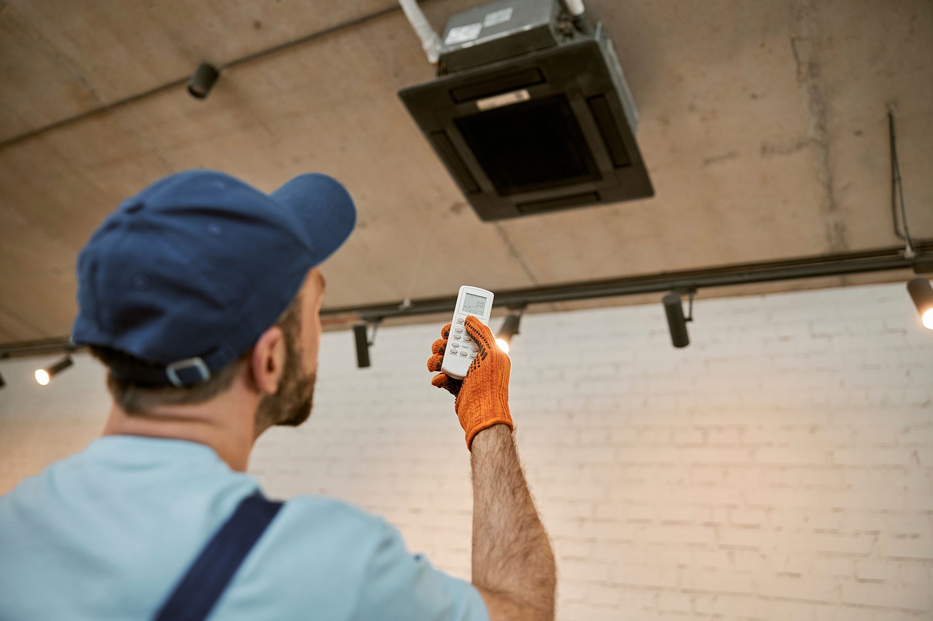 A man is holding a remote control in front of a ceiling fan.