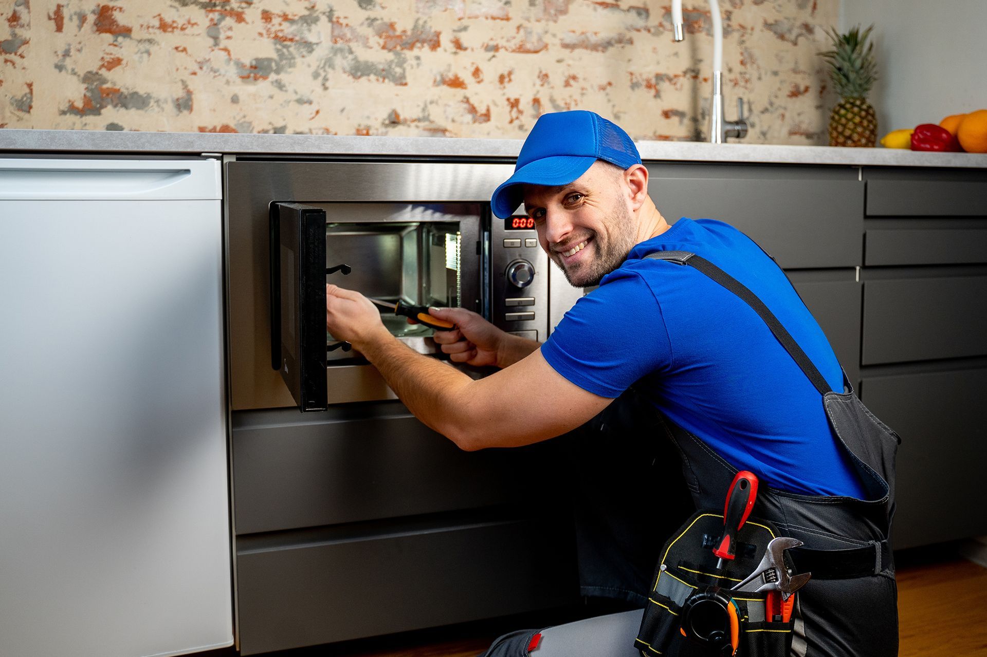 A man is fixing a microwave oven in a kitchen.