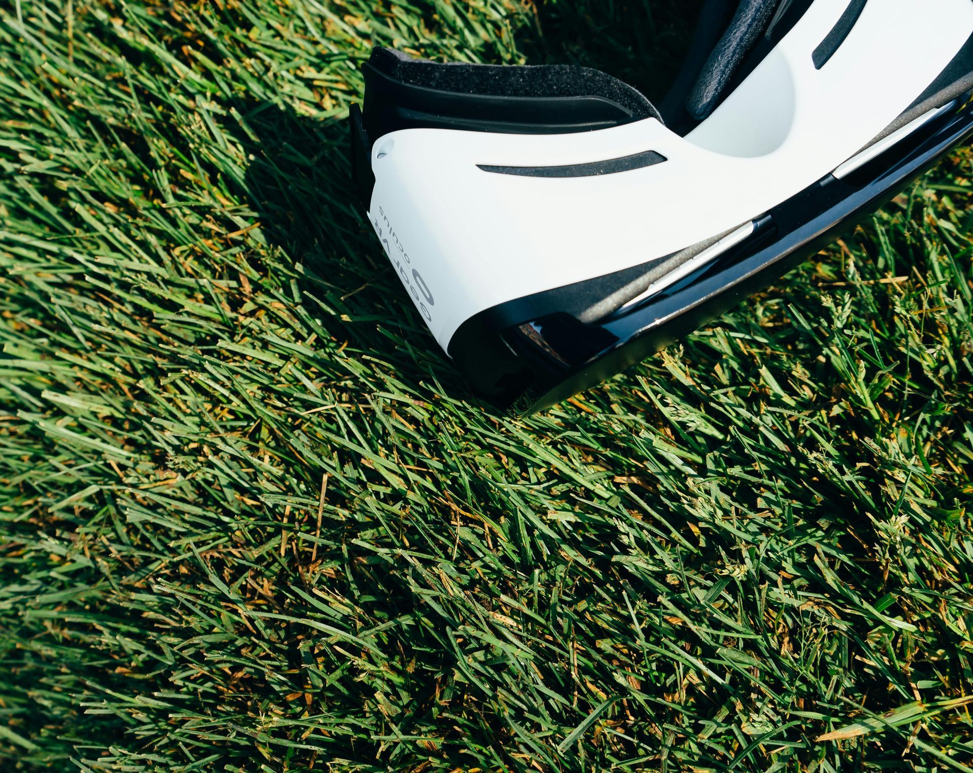 A virtual reality headset is sitting on top of a lush green field.