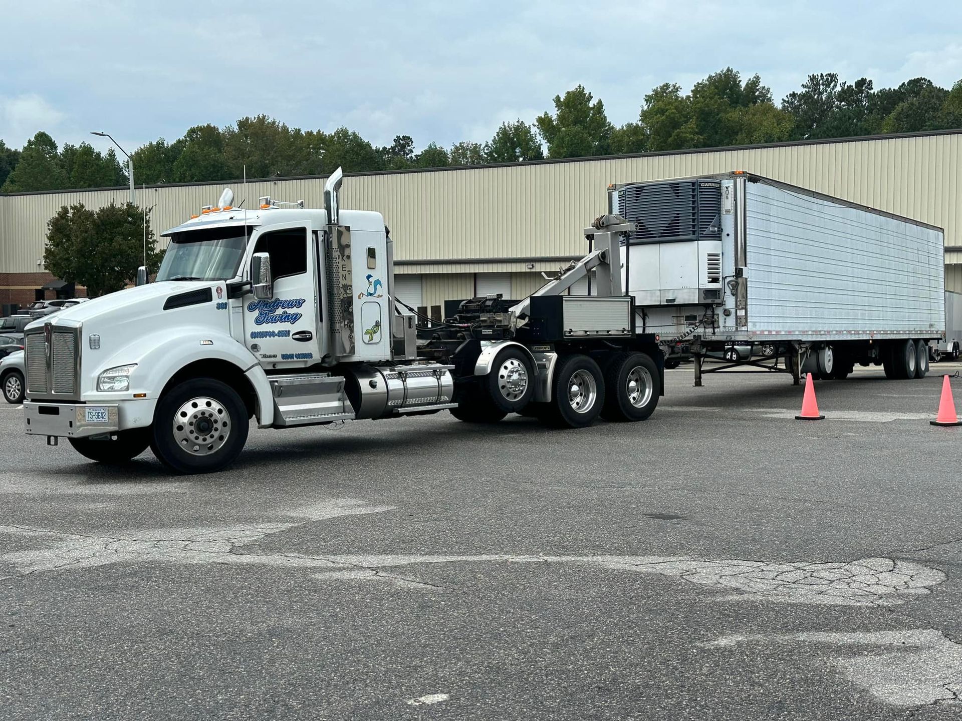 A semi truck is towing a trailer in a parking lot.