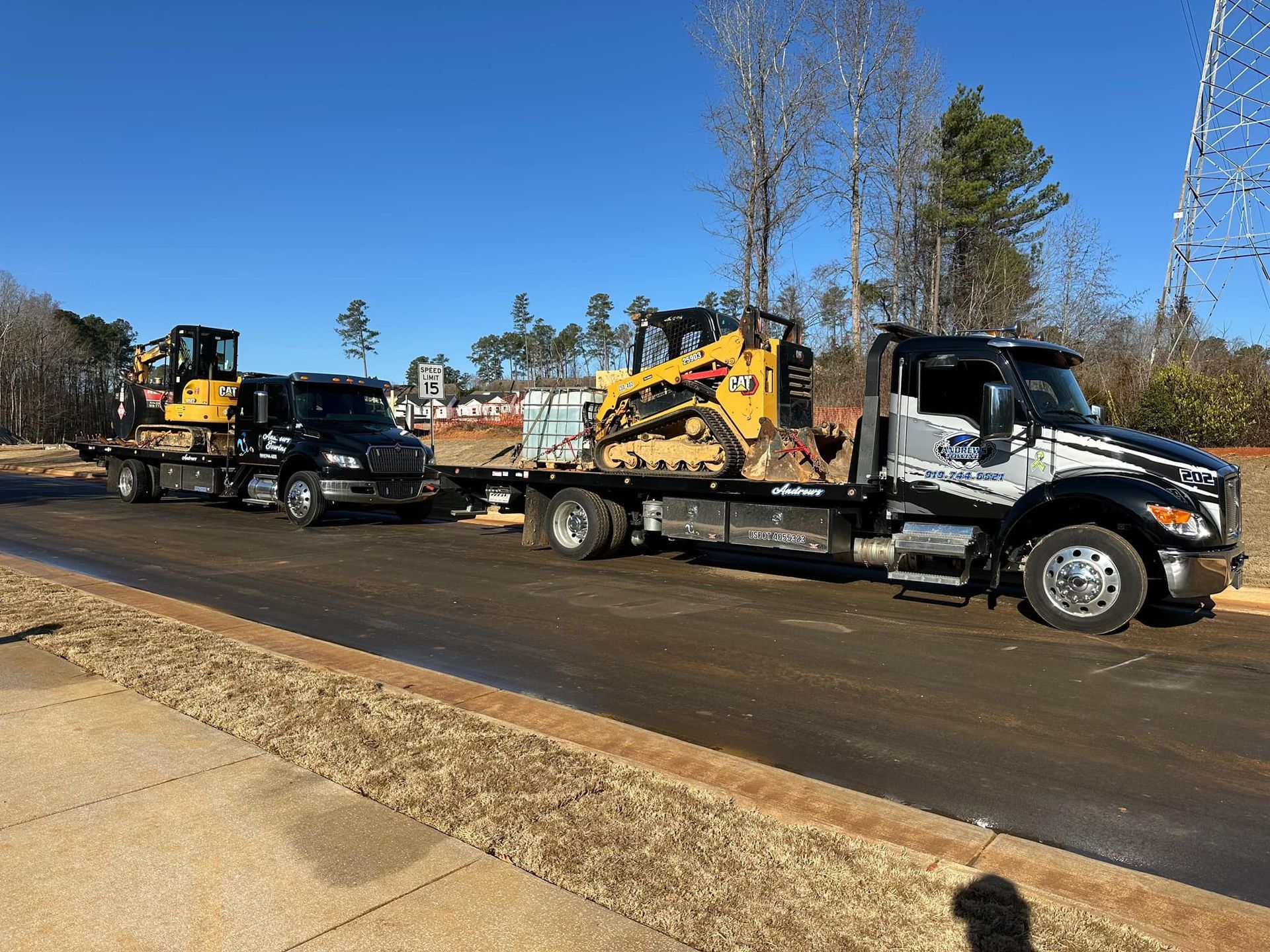 A tow truck is carrying a bulldozer and a truck.