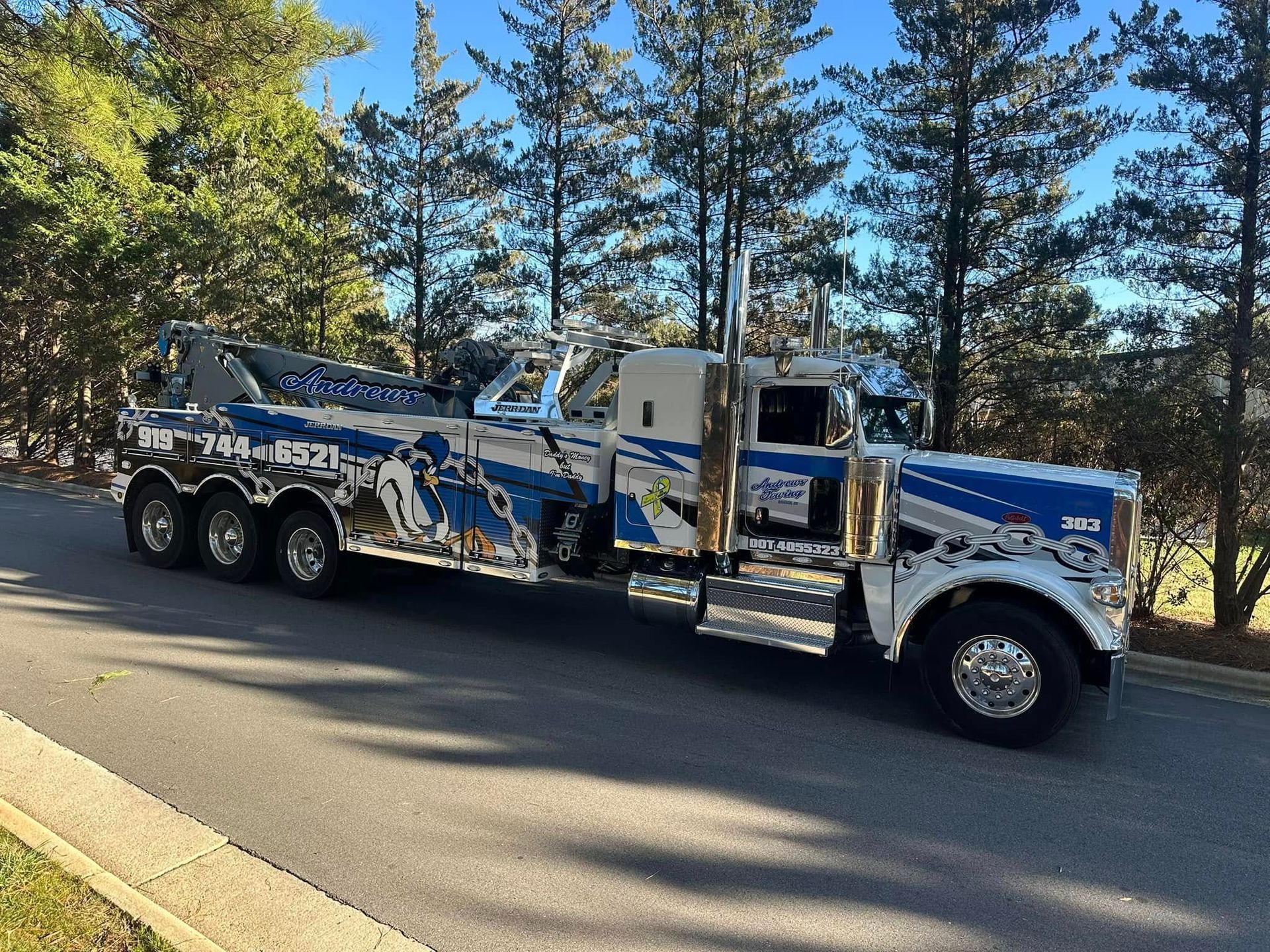 A blue and white tow truck is parked on the side of the road.
