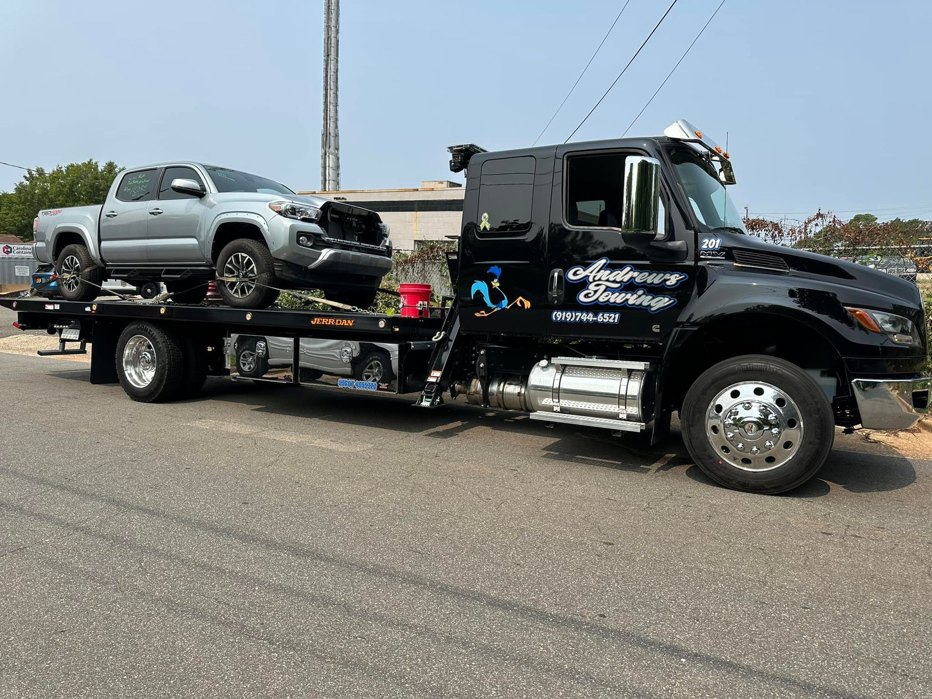A tow truck is carrying a pickup truck and a damaged car.