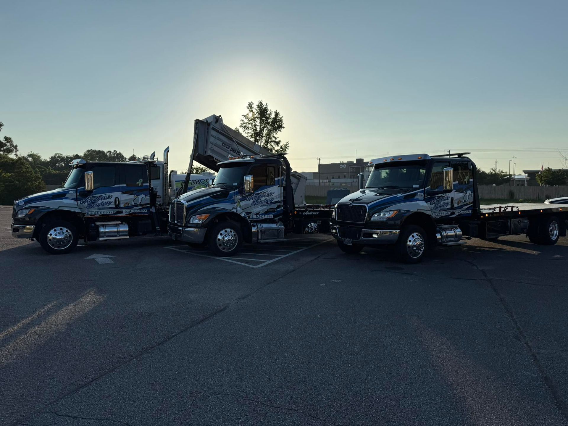 Three tow trucks are parked next to each other in a parking lot.
