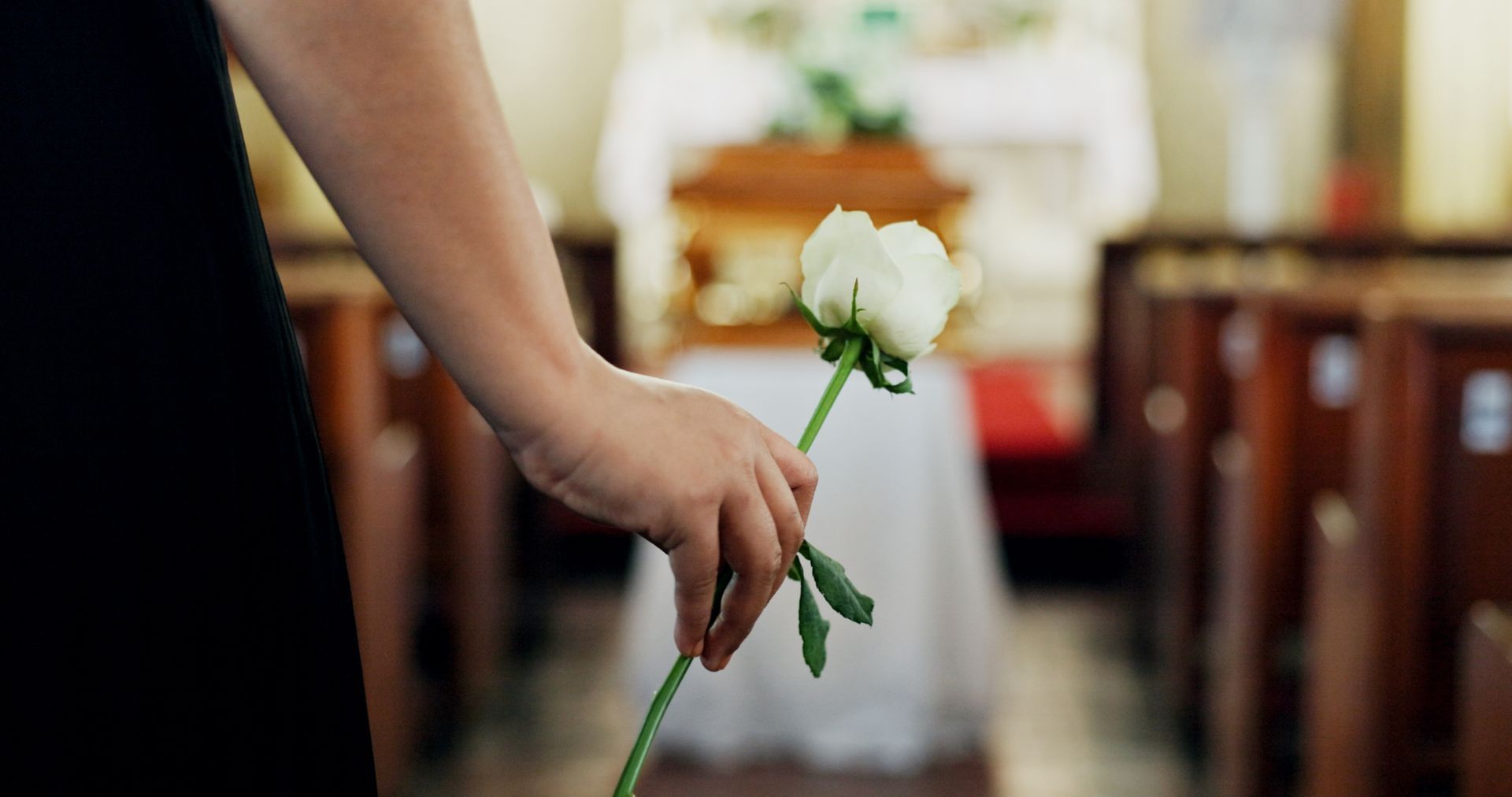 Mourners carry a wooden casket with white flowers at a funeral procession
