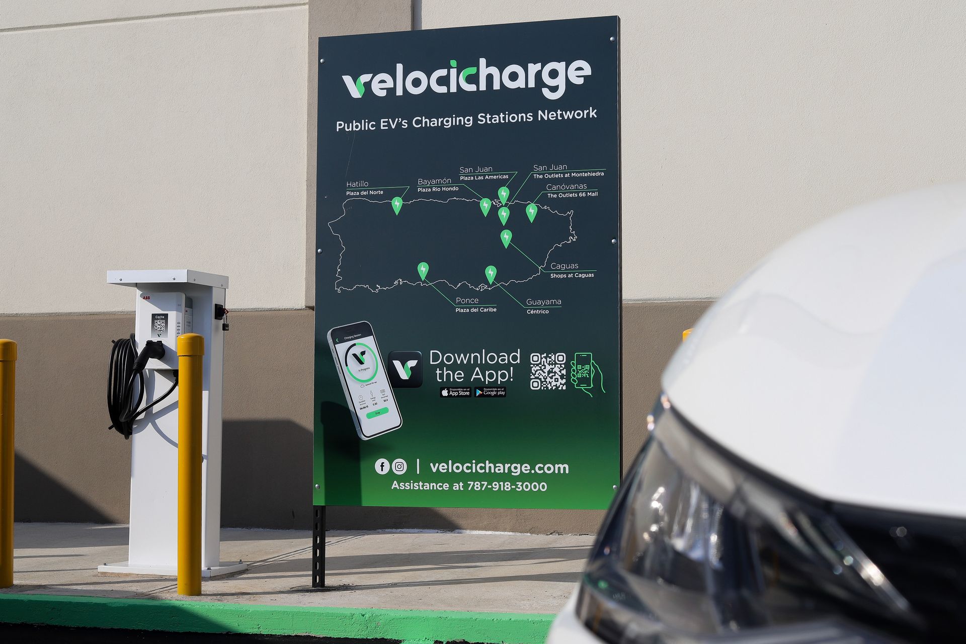 Electric vehicle charging station with a car parked next to a Velocicharge sign.