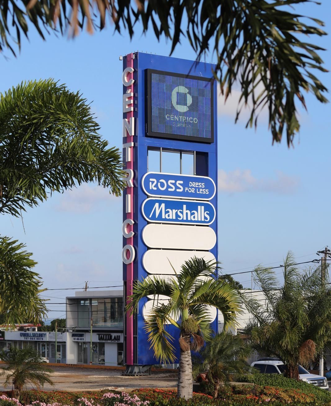 Shopping center sign for Ross Dress for Less and Marshalls beside palm trees and hedges