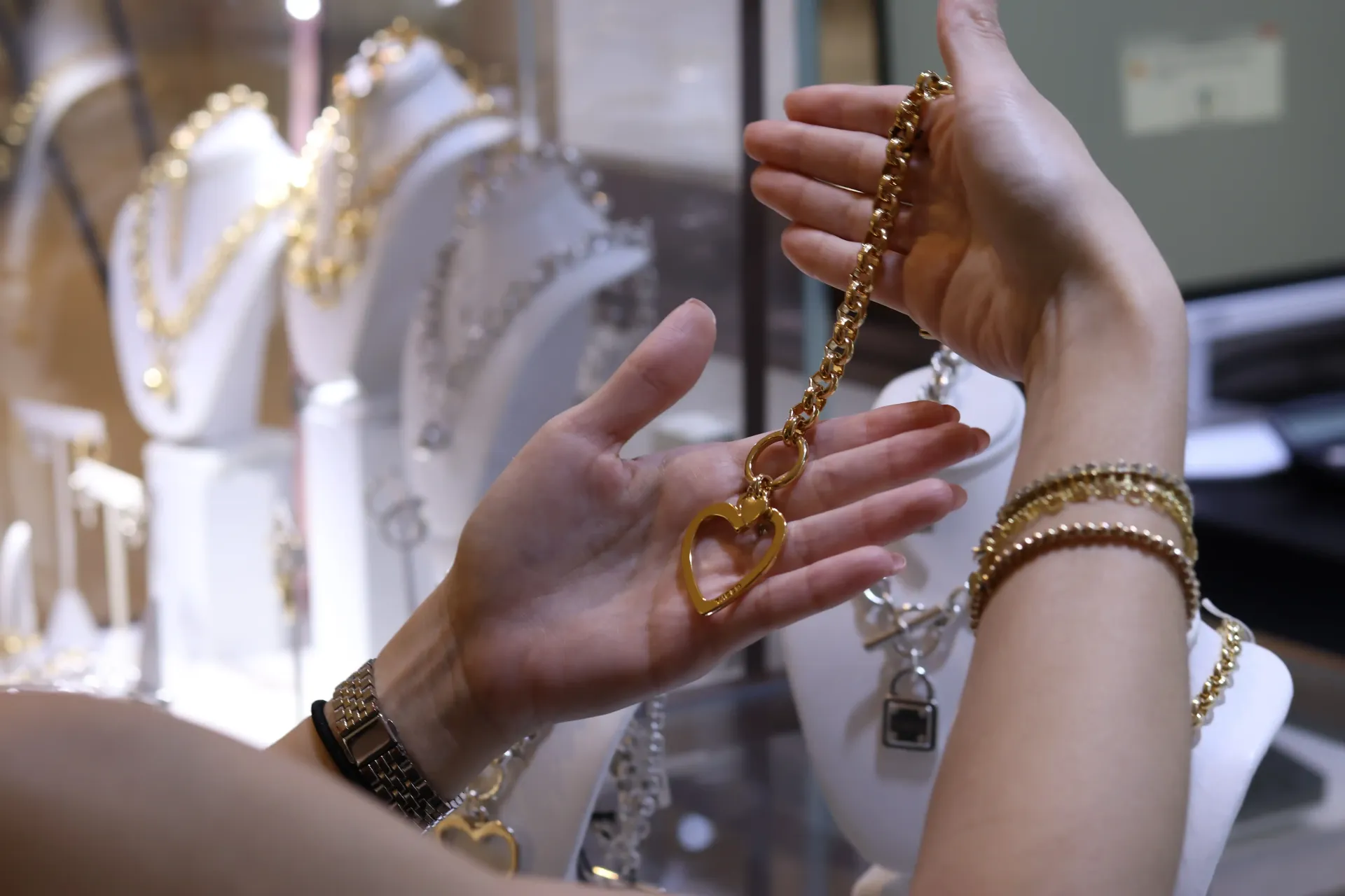 A woman is holding a gold necklace in her hands.